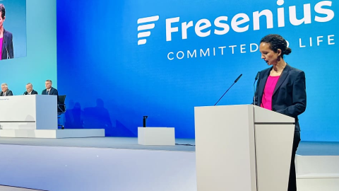 Frau steht auf Bühne vor einem Redepult