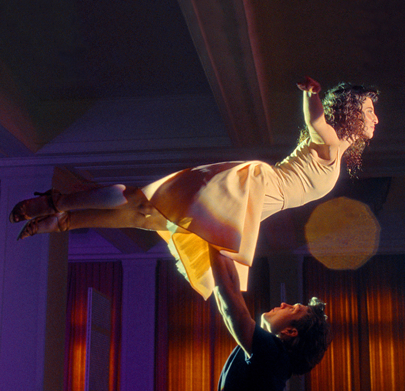 Ein junges Tanzpaar führt den hohen Flieger in einem Saal auf.